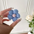 Detaillierte Textur der blauen Cord-Blumen-Handyhalterung mit weicher rosa Mitte in Hand - Blau