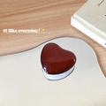 Vista macro di un supporto per telefono a cuore bordeaux su specchio e legno - Supporto a Base Bianca / Borgogna