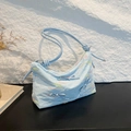 Hellblaue Shopper-Tasche mit Wellenstickerei und 3D-Schleife vor Steinhintergrund - Blau