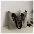 Dettaglio della borsa tote in tela grigio-verde con cinghie marroni e testo artistico - Verde