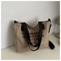 Dettaglio borsa tote beige in tela con tracolla nera e stampa slogan minimalista chic - Cachi