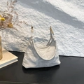 Minimalist silver metallic hobo tote bag with marble bead handle on black wood surface - Gray