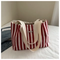 Detalle de bolso tote de lona a rayas rojas y blancas en cama blanca con chaqueta - Rojo