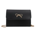 Elegant black leather crossbody chain bag with a gold bow buckle on white background - Black