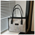Primer plano de bolso tote beige con bordados ondulados de colores y detalles en cuero negro - Blanco