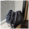 Close-up of dark blue denim bucket bag with drawstring closure and two front pockets - Dark Blue