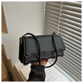 Detail view of the black crossbody bag featuring a wavy flap design and gold hardware - Black