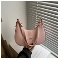 Pink crescent underarm bag with silver bow accent shown in a hand-held lifestyle shot - Pink