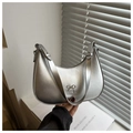 Detail of silver crescent hobo bag with metallic bow charm on minimalist background - Silver