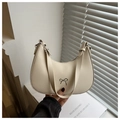 Close-up of a creamy half-moon bag featuring a silver metal bow accent and smooth texture - White
