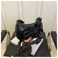 Close-up of black patent leather hobo bag with bow detail and pleated shoulder strap - Black