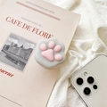 Dettaglio di un supporto per telefono a forma di zampa di gatto 3D su una rivista - Zampa Grigia