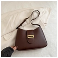 Detail of dark brown leather crescent bag with golden buckle on a beige blazer - Brown