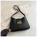 Detail of elegant black underarm bag with gold textured buckle on beige suit background - Black