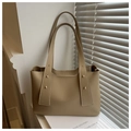 Detail of minimalist beige tote bag showing smooth matte leather and gold rivet accents - Khaki