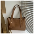 Detail of caramel brown tote bag featuring golden rivet accents and matte leather finish - Brown