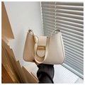 Primer plano de la hebilla dorada ajustable y la textura de cuero del bolso hobo crema - Blanco