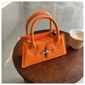 Kleine hellorangefarbene PU-Lederhandtasche mit silbernem Stern auf dunklem Holztisch - Orange