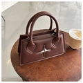 Sac à main en cuir marron avec pendentif étoile argentée sur une table en bois - Marron