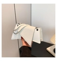 White faux crocodile leather trapezoid handbag with silver chain strap shown in lifestyle shot - White