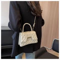 Close-up of beige quilted crossbody bag with gold metal hardware and round handle detail - Off White