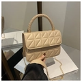 Detail van beige gewatteerde handtas met geweven handvat en gouden ketting in een spiegelreflectie - Khaki