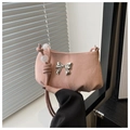 Detail of nude pink shoulder bag featuring silver bow accent and beaded knot strap - Pink