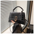 Detalle del mini bolso negro de piel de cocodrilo con un elegante cierre de metal dorado - Negro