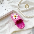 Close-up of pink clog phone stand with flower and smiley face charms on white fabric - Rose Red