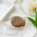 Detailed macro shot of caramel brown taiyaki phone socket showing matte resin texture - Brown