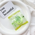 Close-up of green melon bread squeeze toy in clear packaging on a white plate - Green (Melon Snack Bag)