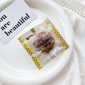Detail of yellow checkered snack packaging on white plate with pearl decor - Brown (Chocolate Snack Bag)