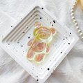 Dettaglio del supporto per telefono a forma di orsetto giallo con finitura laser iridescente - Supporto Orso / Giallo Trasparente Iridescente