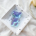Macro shot of an iridescent bear phone socket with purple and blue laser reflection - Bear Holder / Iridescent Transparent Blue