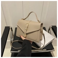 Dettaglio borsa a tracolla in pelle beige con fibbia in metallo su una sedia - Cachi