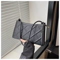 Close-up of black quilted shoulder bag with drawstring knot strap and embossed texture - Black
