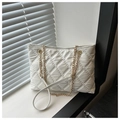 Detail einer weißen Stepptasche mit goldener Kette vor einem Fensterladen-Hintergrund - Weiß