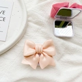Detail showing solid color 3D bow phone stand with integrated vanity mirror feature - Pink