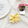 Detail of a 3D bow phone socket and folding makeup mirror on white knitted fabric - Yellow