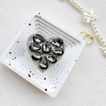 Macro detail of luxury heart-shaped phone grip with gray crystals and white rhinestones - Gray