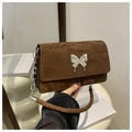 Close-up of brown quilted bag with silver butterfly clasp and chain detail - Brown