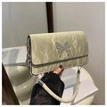 Détail du sac plissé crème avec boucle papillon en métal argenté et bandoulière chaîne - Vert