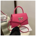Close-up of bright pink leather crossbody bag with a large silver metal bow buckle - Rose Pink