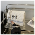 Detail einer weißen Stepptasche mit silberner Schleifenschnalle und verstellbarer Kette - Weiß