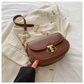 Detalle de bolso silla de montar marrón con cierre en T dorado sobre blazer beige - Marrón
