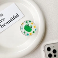 Vue détaillée du support de téléphone rond avec un mignon crapaud vert et des pois - Grenouille