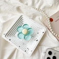 Detail view of light blue translucent flower phone grip on decorative white tray - Green Flower