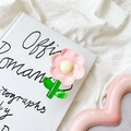 Vue détaillée du support de téléphone en fleur de tulipe rose sur un fond de livre épuré - Fleur à Feuilles Vertes en Cristal / Rose
