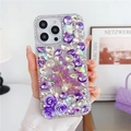 Dettaglio custodia iPhone di lusso con rose viola, perle e cristalli tenuta in mano - Viola Metallico / iPhone 15 Pro Max