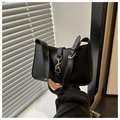 Detalle de un bolso sobaco de cuero negro con cierre de metal dorado sostenido por una modelo - Negro